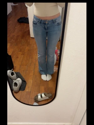 Ljusblå bootcut jeans - Säljer ett par ljusblå bootcut jeans med hög midja och klassiska fem fickor. Jeansen har en snygg utsvängd passform från knät och är tillverkade i mjukt denimtyg. Perfekta för en avslappnad och trendig look. Det är storlek xs i midja och 32 längd 