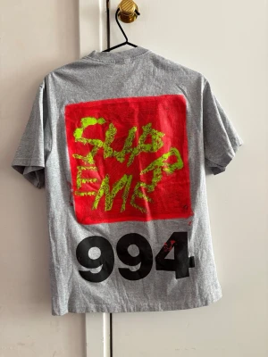 Helt ny Supreme t-shirt med unikt tryck  - Helt ny Supreme tisha med lite schysstare tryck på ryggen. Givetvis sitter taggen kvar ✅ Väldigt unik och perfekt för dig som vill ha en lite ball och avslappnad stil 😎🤙. Funkar ju såklart för de allra flesta stilerna. Om ni har några fundering kring storlek eller t.ex. vill ha fler bilder på trycket är det bara o höra av sig till mig. // Victor 😁✌️