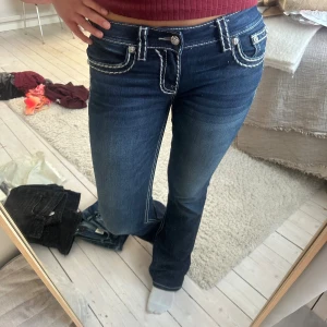 Miss me jeans - Säljer ett par mörkblå bootcut jeans med tydliga vita kontrastsömmar och dekorativa fickor fram. Jeansen har låg midja och är från MISS ME. Superfina och knappt använda!! Passar längre och kortare personer