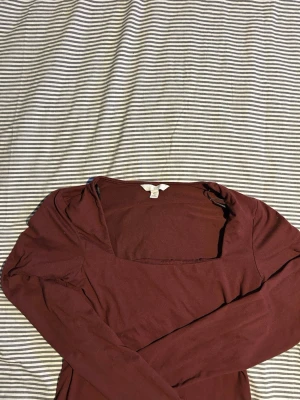 Vinröd långärmad topp H&M - Snygg vinröd långärmad topp från H&M med fyrkantig ringning. Tillverkad i mjukt bomullsmaterial som känns skönt mot huden. Perfekt att styla med jeans eller kjol för en trendig look.