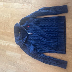 Mörkblå kabelstickad tröja Polo Ralph Lauren - Kabelstickad Ralph lauren storlek M, knopprig och använd ganska ofta( knopparna går och få bort med hjälp av maskin) väldigt litet hål vid vänster sidan men knappt synligt, säljes pga för liten 🤩🙌