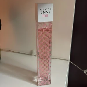 Gucci Envy Me Parfym - Säljer en elegant och lyxig parfym från Gucci, modellen Envy Me. Flaskan är rektangulär och genomskinlig med rosa Gucci-loggor över hela ytan. Korken är vit med texten 'Gucci Envy Me' i svart och rosa. Perfekt för den som vill ha en sofistikerad och feminin doft. Flaskan är i utmärkt skick och nästan full. Säljer då den inte passar mig och där med inte kommer till användning 💖Ny pris är över 3000, vet inte exakt då jag fick den i födelsedagspresent för länge sen och den nu har utgått i sortimentet.