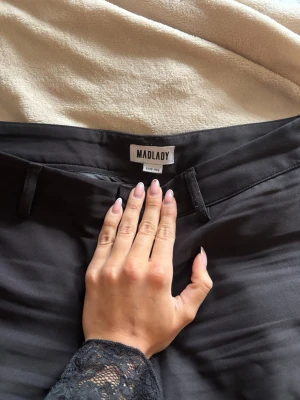 Svarta kostymbyxor EU 36 – Madlady, mid waist - Svarta kostymbyxor från Madlady 🤍  Mid waist och tight passform som sitter perfekt runt midja och rumpa, med en smickrande silhuett. Perfekt längd och riktigt trendiga för både vardag och fest ✨  Storlek EU 36. Jag är 170 cm och brukar ha storlek S/M – byxorna sitter perfekt på mig.  Använda fåtal gånger, i mycket fint skick. En trendig och stilren byxa som passar året runt.
