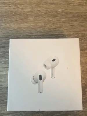 Apple AirPods Pro trådlösa hörlurar - Säljer ett par vita Apple AirPods Pro (2grn) med laddningsetui. De har en stilren och kompakt design med silikonproppar för bättre passform och brusreducering. Perfekta för musik, samtal och gaming. Levereras i originalförpackning.