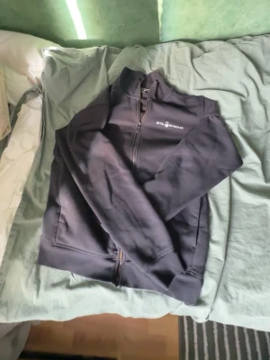 Svart zip hoodie från Salming - Säljer en svart hoodie med dragkedja från Salming. Hoodien har hög krage, två fickor fram och diskret logga på bröstet samt en liten logga i nacken. Tillverkad i mjukt sweatshirtmaterial, perfekt för chill eller träning.