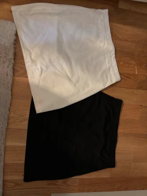 Två enkla kjolar i svart och vitt - Säljer två stilrena kjolar, en i vitt och en i svart. Båda har en rak, kort passform och är perfekta att matcha med olika toppar. Materialet mjukt och bekvämt. Perfekt basplagg för garderoben. Tror båda är i storlek xs och de är från SHEIN. Därav de billiga priset 