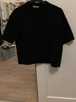 Svart stickad tröja Gina Tricot - Säljer en svart stickad tröja från Gina Tricot med korta ärmar och rund hals. Tröjan är i ett mjukt, fluffigt material och har en enkel, stilren design som passar till det mesta. Perfekt för dig som gillar basic men ändå vill ha något mysigt.