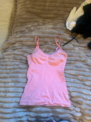 Rosa träningslinne - Snyggt rosa linne med smala justerbara axelband och figurnära passform. Perfekt att bära som lager eller för en enkel look. Mjukt material som känns skönt mot huden.