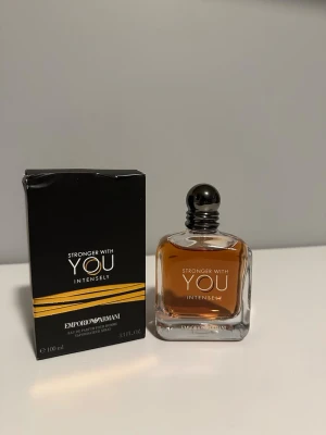 Emporio Armani Stronger With You Intensely - Emporio Armani Stronger With You Intensely är en herrparfym i en elegant, fyrkantig glasflaska med svart rund kork. Doften kommer i en svart kartong med guldiga detaljer och rymmer 100 ml. Flaskan har en varm bärnstensfärgad vätska och en stilren design.