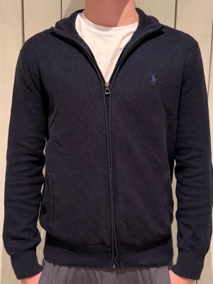 Marinblå zip-kofta från Polo Ralph Lauren - Blå Ralph lauren kofta perfekt inför vår. Inte använd på länge därför lite skrynklig. Bra kvalite. Storlek M. Pris kan diskuteras. 