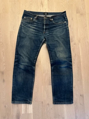 A.P.C. Japanese Selvedge - ljusblå - size 31 - Säljer ett par A.P.C. New Standard i klassisk ljusblå/blå denim. En ikonisk modell från A.P.C. med straight fit, något mer utrymme i låren och avsmalnande ben, så nästintill slim/straight! Storlek 31, skick 8/10.   Tillverkade i japansk selvedge denim av hög kvalitet som formar sig efter kroppen och får snygga naturliga fades över tid. Dessa har redan utvecklat fin patina som ger dem karaktär. Vid fler frågor får du gärna skriva och vid snabb affär går pris att diskuteras!