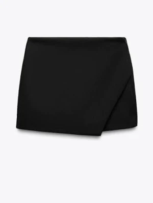 Svart kostymkjol från Zara  - Stilren svart kjol från Zara med omlottdesign framtill. Den har insydda shorts också. Klassisk rak passform och kort längd, perfekt för en trendig look. Tillverkad i ett mjukt tyg som ger en snygg siluett. Enkel att matcha med olika toppar och accessoarer.