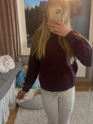 Vinröd hoodie med ficka framtill - Säljer en vinröd hoodie med huva och  magficka. Hoodien har långa ärmar, ribbade muddar och dragsko i huvan. Perfekt för dig som gillar en enkel och stilren look. Materialet känns mjukt och skönt mot huden.