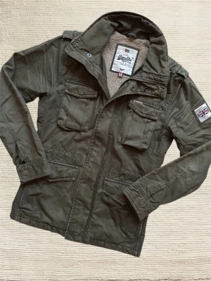 SUPERDRY FIELDJACKET  - En mycket trevlig fieldjacket av märket Superdry i en extremt snygg grön färg! Perfekt skick på denna! Hör av dig vid frågor!