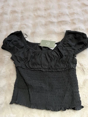 Svart puffärmad topp från HM - Trendig gråsvart topp från HM med puffärmar🩷Aldrig använd storlek 170 med är som xs