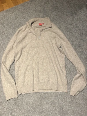 Beige halvzip tröja från Uniqlo - Mysig beige tröja från Uniqlo med halv dragkedja och hög krage. Perfekt för lager på lager och enkel att matcha med olika outfits. Tillverkad i mjukt material och har långa ärmar samt avslappnad passform.
