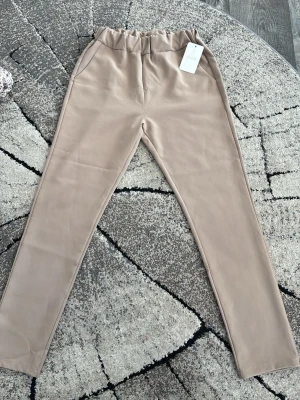 Beige leggings från My Look - Snygga beige leggings från My Look med hög midja och resår i midjan för extra komfort. Tillverkade i ett mjukt och stretchigt material som sitter skönt på kroppen. Perfekta att matcha med oversized tröjor eller hoodies.