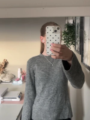 Grå stickad tröja med utsvängda armar  - En enkel grå stickad tröja med rund hals och långa ärmar. Tröjan har ribbstickade muddar vid ärmslut och nederkant. Perfekt att matcha med jeans för en avslappnad look. Sälje eftersom att den aldrig blivit använd😊 Priset kan diskuteras!!!