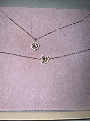 Lily and rose gnistrande set -  halsband och matchande armband med runda hängen, dekorerade med gnistrande stenar i silverfärg med en babyrosa större sten.