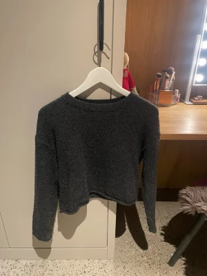 Mörkgrå stickad tröja från ZARA - Mysig mörkgrå stickad tröja från ZARA med enkel design och rund hals. Tröjan har långa ärmar och är gjord i ett mjukt, fluffigt material som passar perfekt till kalla dagar. Enkel att matcha med jeans eller kjol.