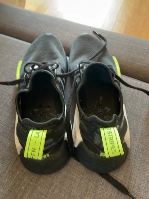 Svarta Adidas sneakers med neon-detaljer - Säljer ett par Adidas NMD_R1 i svart med neon-gula detaljer 🖤💛   Använda endast 3 gånger – i mycket fint skick!  Bekväma och stilrena sneakers som passar till allt, både vardag och streetwear. Inga större slitage, sulan och ovandelen är i toppskick.  Storlek: 41-42 Nypris: ca 1500kr Säljes för: 300kr  Hör av dig vid frågor eller fler bilder ✌️