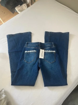 Blå bootcut jeans med spetsdetalj - Såå fina blå bootcut jeans från Meet Me There med spetsdetalj på bakfickorna, från Filippas kollektion. Storlek s/m. Helt nya, aldrig använda, prislapp kvar! Lägg gärna prisförslag! Nypris 730-:💗