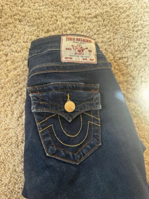 Mörkblå True Religion jeans - Säljer ett par mörkblå jeans från True religion som är uppsydda och innerbenslängden är ca 79/80cm men går att  lägga ner 2cm, storlek 24💞