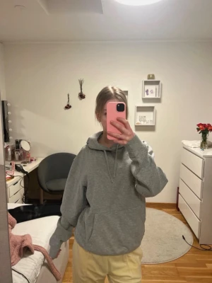 Grå hoodie från Kappa - Säljer en klassisk grå hoodie från Kappa med huva och dragsnören. Hoodien har en stor magficka och  Kappa-logga på bröstet. Perfekt för chill dagar eller när du vill ha en enkel och snygg look. Tillverkad i mjukt material för extra komfort.