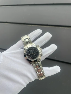 Seiko Daytona Mod - Specifikationer: Storlek: 39mm Urverk: VK63 (Mechaquartz) Material: 904L Rostfritt Stål Glas: Sapphire Glas Tavla: Grå Camo Bezel: Silver Armband: Viklås och Justerbart  Krona: Screw Down Vattentålighet: 30 Meter Klocklåda ingår