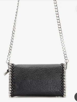 Svart axelremsväska med kedja - Snygg svart handväska i strukturerat konstläder med silverfärgad kedjerem och detaljer längs kanterna. Väskan har en rektangulär form och coola metallinslag som ger en edgy vibe. Perfekt för dig som gillar stilrena accessoarer med attityd.