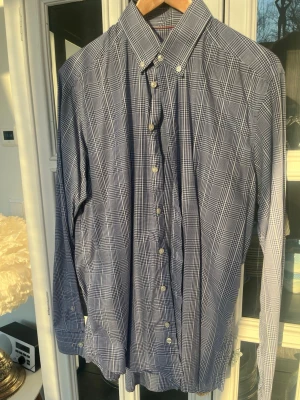 Blårutig skjorta från Eton slim fit - Snygg blårutig strykfri skjorta från Eton i slim fit-modell. Skjortan har klassisk krage, vita knappar och långa ärmar. Tillverkad i mjuk bomull som känns skön mot huden. Perfekt för dig som gillar stilrena och tidlösa plagg. Storlek 16(41) 