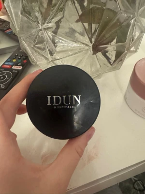 IDUN Minerals Saga Mineral puder  - Mineral puder från IDUN Minerals i nyansen Saga 033 Neutral Light. Kommer i en rund burk med svart lock och silvrig text. Innehåller 7 g puderfoundation med SPF 15 och vegansk formula. Perfekt för en naturlig och lätt täckning.