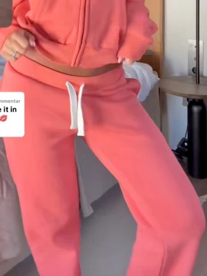 Coral low waist mjukisbyxor - Säljer ett par russemerch liknande mjukisbyxor i trendiga färgen korall och med vit dragsko. Byxorna har en avslappnad passform och är tillverkade i mjukt sweatshirtmaterial, perfekta för chill dagar och sommarn🌺☀️🏝️Hae lagad defekt, be om bild vid intresse!