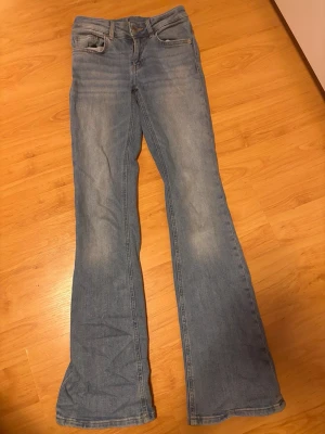 Ljusblå bootcut jeans - Säljer ett par ljusblå bootcut jeans med klassisk ljusblå färg. Jeansen har normal midja och är tillverkade i denim med stretch för extra komfort. Perfekt för dig som gillar en avslappnad och trendig look. Dessa jeans är i storlek xs/s skulle jag säga och dem är från lager 157 och original pris på dem är 400. Dem är även väll bevarade och inte alls slitna i varken tyg midja eller nedre del vid foten☺️