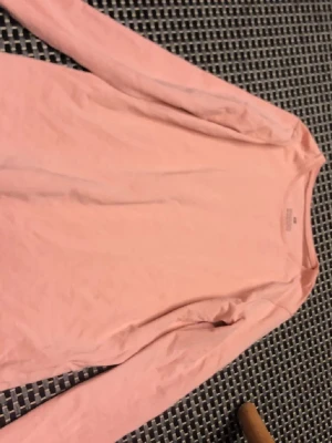 Ljusrosa långärmad topp från H&M - En enkel och stilren ljusrosa långärmad topp från H&M. Tillverkad i mjuk bomull med rund halsringning och normal passform. Perfekt att matcha med jeans eller kjol för en clean look.