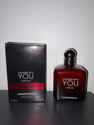 Emporio Armani Stronger With You Parfum - Emporio Armani Stronger With You Parfum i en elegant mörkröd glasflaska med rundad form och svart kork. Flaskan rymmer 100 ml och har en stilren design med vit text. Kommer med originalkartong i svart med röda detaljer.