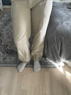 Beiga cargobyxor med resår - Säljer ett par beiga cargobyxor med resår i bensluten och avslappnad passform. Byxorna har fickor bak och är perfekta för en chill och bekväm stil. Materialet känns mjukt och lätt, perfekt för att hänga hemma eller ta det lugnt.