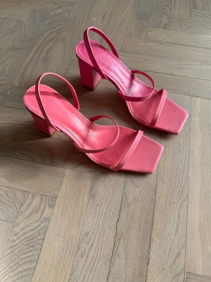 Rosa klackar MANGO - Snygga klackar i rosa med fyrkantig tå och bred blockklack. Skorna har tunna remmar över foten och öppen häl. Tillverkade i ett material som ser ut som konstläder. Perfekta för dig som vill sticka ut med färg.