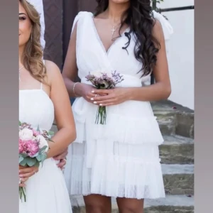 Vit omlottklänning med volanger - Superfin vit kortklänning med omlottliv, djup v-ringning och flera lager volanger i kjolen. Perfekt för student, dop, fest osv. Den är i storlek M men passar även dem som är XS/S vilket jag är. Använd endast en gång. Priset kan diskuteras!