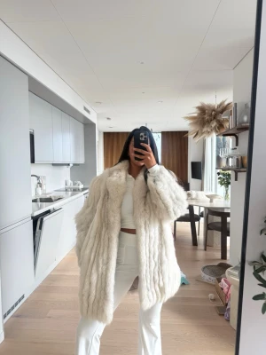 Vit  päls med oversized passform - Säljer en supermjuk och fluffig vit päls kappa med oversized passform. Kappan har bred krage och långa ärmar, perfekt för att hålla sig varm och stylish under kalla dagar. Enkel att matcha med olika outfits för en trendig look.