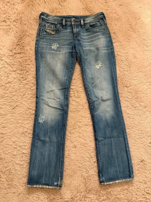 Blå slitna raka jeans - Säljer ett par blå jeans med raka ben och slitna detaljer på framsidan. Jeansen är i storlek 28 och är från DieselIndustry. ÄLSKAR dessa jeans men har tyvärr blivit försmå för mig!💕💕💕