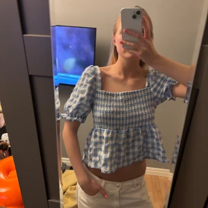 Blårutig  topp med puffärm - Supersöt blårutig topp med smockad överdel och puffiga korta ärmar. Toppen är i storlek L, men passar mig som har S 