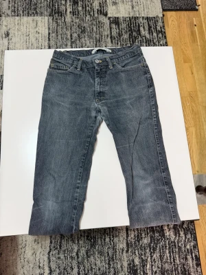 Mörkblå raka jeans - Säljer ett par mörkblå jeans med rak passform och klassisk femficksdesign. Jeansen har en något tvättad look och stängs med dragkedja och knapp. Perfekta till en avslappnad stil och passar till det mesta i garderoben.