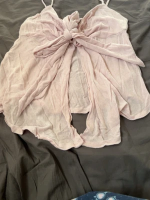 Ljusrosa ärmlös nattlinne med knyt - Supersött ljusrosa nattlinne med tunna axelband och stor knytning framtill. Modellen är ärmlös och har en loose passform som ger en avslappnad känsla. Tillverkat i mjuk bomull, perfekt för varma sommarnätter.