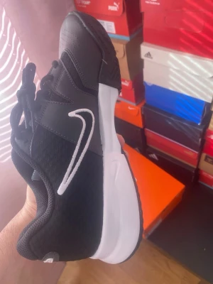 Nike Claybreaker Svart Vit - Säljer ett par snygga svarta Nike sneakers med vit sula och vit swoosh på sidan. Skorna har låg profil, mesh och syntetmaterial i ovandelen samt klassisk snörning. Perfekta för dig som vill ha en stilren och sportig look.