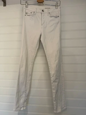 Vita shaping jeans med smal passform - Snygga vita shaping jeans med smal passform och klassisk femficksdesign. Jeansen har normal midja och raka ben, perfekta för en clean och fräsch look. Materialet är stretchigt för extra komfort och passform. Snygga slitningar på bakfickor. 