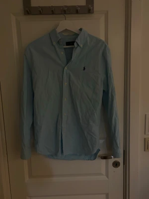 Ljusblå skjorta från Ralph Lauren - Bilder kommer ej tas när jag har på mig den, har ej tid. Passar runt 175-180. Sitter fint på mig som är 178. Skicket är i nyskick. Endast seriösa köpare, inga byten eller annat. Storlek S, passar S. Säljer allt billigt då jag inte har tid med att lägga upp och diskutera pris