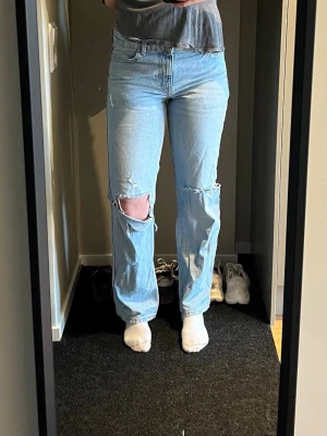 Ljusblå raka jeans med hål vid knäna - Säljer ett par ljusblå mortise jeans från Zara med raka ben och slitna detaljer vid båda knäna.  