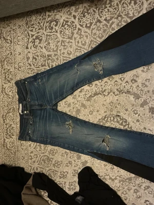 Blå slitna bootcut jeans - Blåa bootcut jeans som jag sytt ut med andra svarta jeans, jeansen har hål och jag söljer då dem inte kommer till användning längre💕