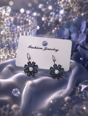 Blå blommiga örhängen i silverfärg - Snygga örhängen i form av blommor med blå kronblad och silverfärgad mitt. Hängande modell med metallkrok. Perfekta för att ge din look en färgklick och en söt touch. Passar dig som gillar unika och trendiga accessoarer.